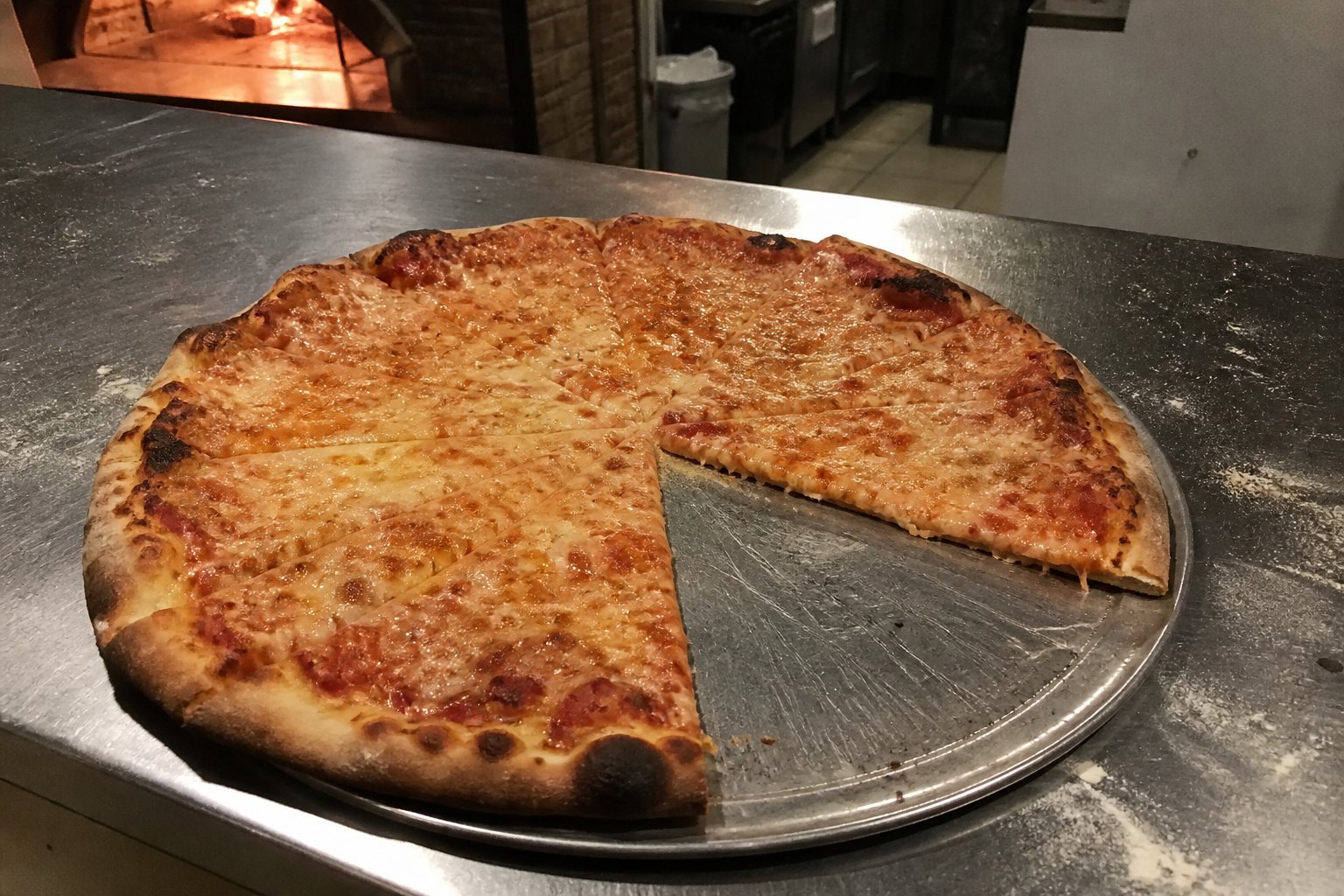 Cheese pizza on a peel, one slice taken.