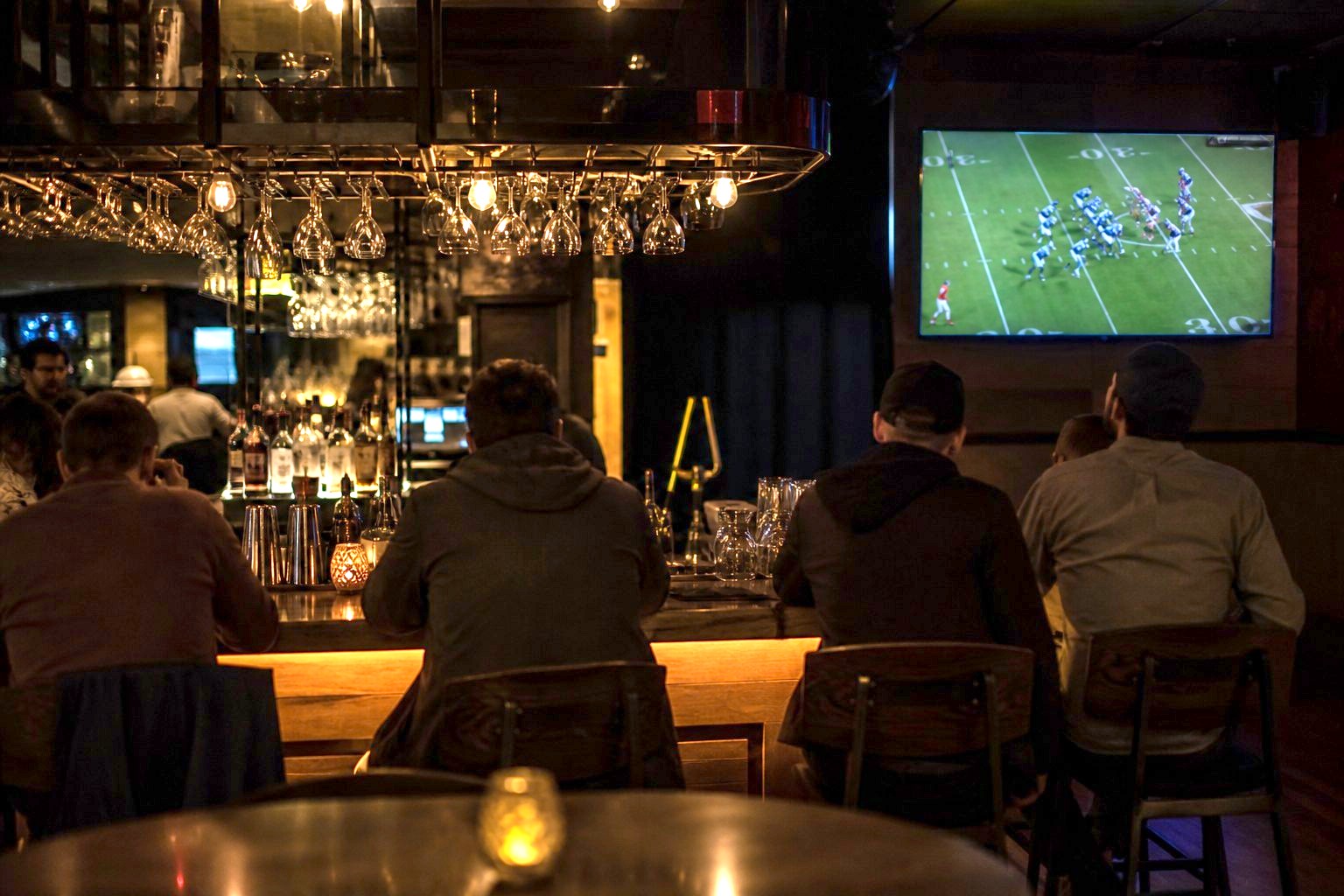 Guests at the bar with the game on.